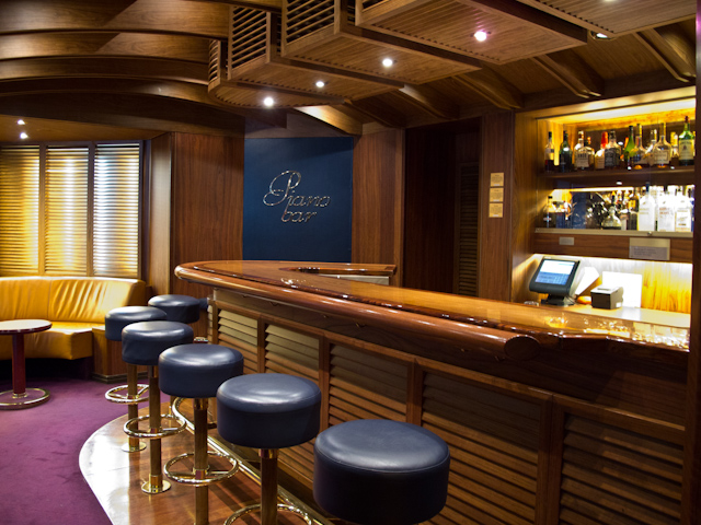 The Piano Bar is another Holland America Line staple. Aboard Zaandam, her rich wood bar and ocean-blue seats create a truly nautical feel. Photo © 2011 Aaron Saunders