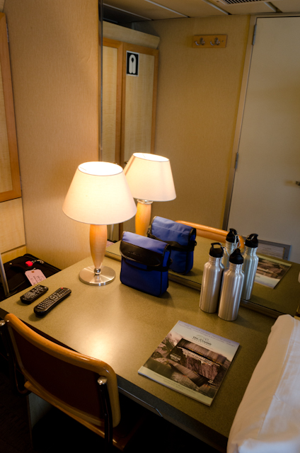 There's a generous desk in each Commander stateroom. Note the included binoculars in the blue case and the dual reusable water bottles. Photo © 2014 Aaron Saunders